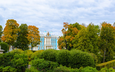 Palace in Baroque style through the autumn leaves on the background of the cloudy sky