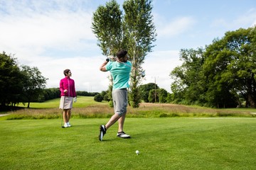 Male instructor assisting woman in learning golf