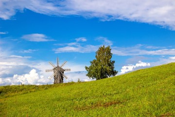 Rural landscape. Traditional wooden windmill on green hill. Kizhi Island. Karelia, Russia. UNESCO heritage landmark