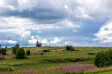 Fototapeta na wymiar Traditional wooden chapel on hill. Summer landscape with cloudy sky. Kizhi Island, Russia