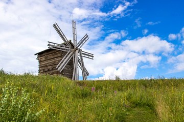 Fototapeta premium Rural landscape. Traditional wooden windmill on green hill. Kizhi Island. Karelia, Russia. UNESCO heritage landmark