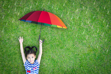 Happy asian girl kid raising hand lying on natural green grass lawn eco bio background holding...