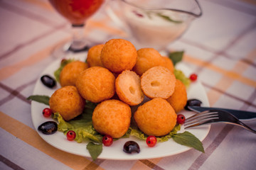 Hot juicy fried cheese balls with sauce on a white plate. Glass of tomato juice.