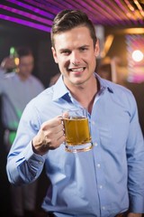 Smiling man holding glass of beer in bar