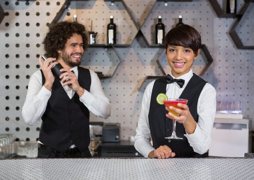 Two bartenders preparing cocktail and serving 