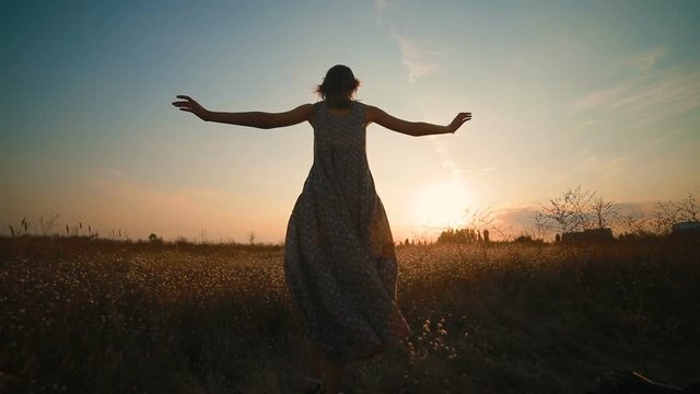 Girl in long beautiful dress running in a field at sunset