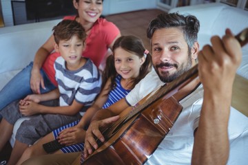 Happy family sitting on sofa with a guitar