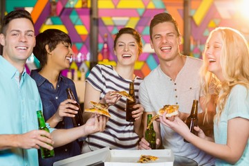 Group of friends having bottle of beer and pizza in party