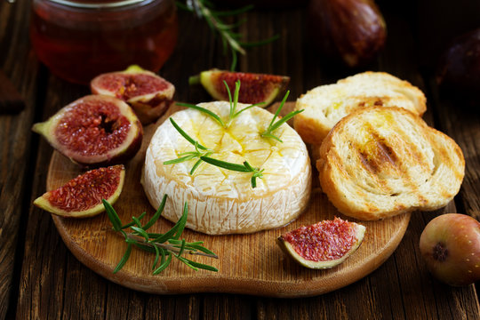 Brie cheese on a wooden board with fresh figs and honey.selective focus.