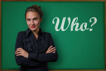 Beautiful young woman teacher (student, business woman) in classical dress standing near a blackboard with the inscription who