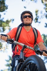 Naklejka premium Male mountain biker riding bicycle in the forest