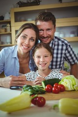 Portrait of happy family leaning on kitchen worktop