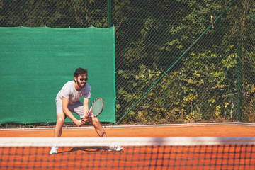 Young man playing tennis on the open court

