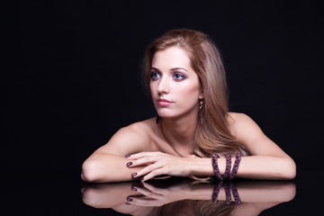Naklejka premium Young beautiful blonde woman sitting at mirror table on black ba