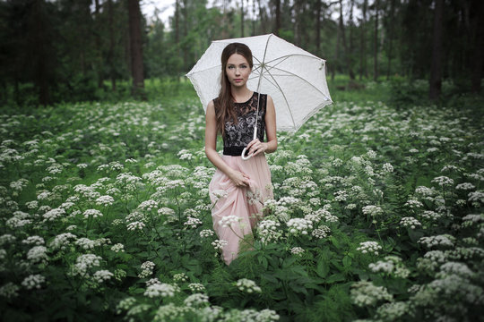 Portrait of beautiful girl with umbrella in nature and white flowers