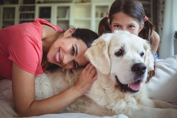 Mother and daughter sitting with pet dog in living room