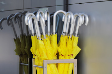 a lot of yellow umbrellas stand in a silver basket in the hotel lobby - Powered by Adobe
