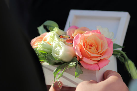 White wooden box for rings with fresh flowers, wooden box for wedding rings in the hands of the best man