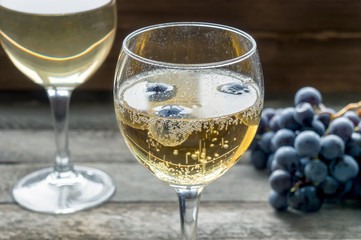 Sparkling wine in a glass. Fresh grape in table.