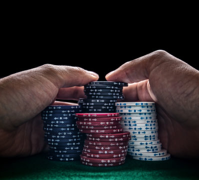 Hände umklammern einen Stapel Pokerchips.