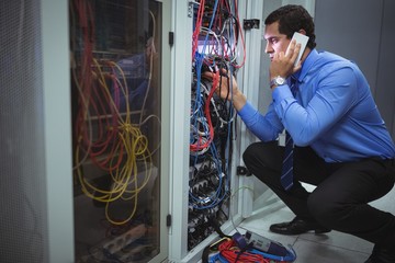 Technician talking on mobile phone while analyzing server