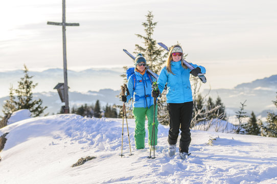 zwei Wintersportlerinnen mit Skiern am Gipfel