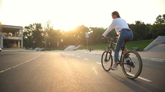 young female rides a bike in park smiling to camera sometimes