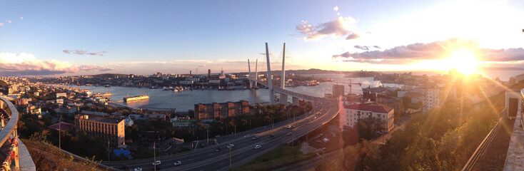 New cable-stayed  bridge in Vladivostok - panoramic view over the town and sea at sunset. A Grand modern building. Panorama of evening Vladivostok, Russia, Primorsky region.
