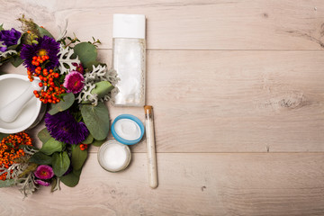 Seasonal skincare products with flowers on a wooden background