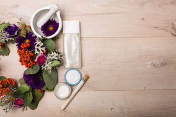 Seasonal skincare products with flowers on a wooden background