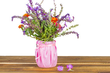 Bouquet of flowers in a jar on a wooden background