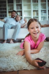 Smiling girl lying on rug and changing channels