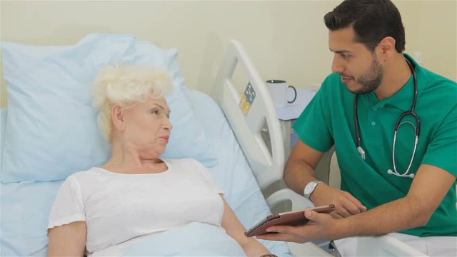 Doctor shows something on his tablet to female patient