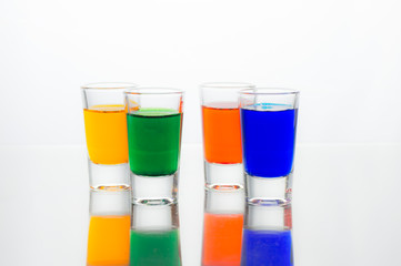 Vodka color shots filled with alcohol on glass bar table