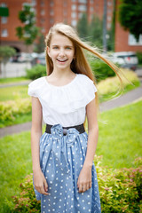 Fototapeta premium Portrait of a beautiful young girl in the Park skirt blouse nature fashion style