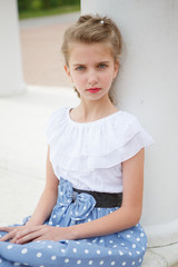 Fototapeta premium Portrait of beautiful young girl near the columns in the Park