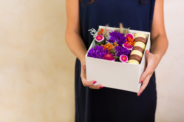 Woman holding a box with flowers and macaroon cookies