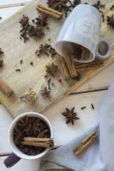 Cups with anise, cinnamon, cloves and pepper on a wooden old table.