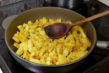 Potatoes in pan wtih wooden ladle