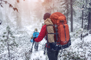 Winter landscape. Tourist in red jacket goes on the hill