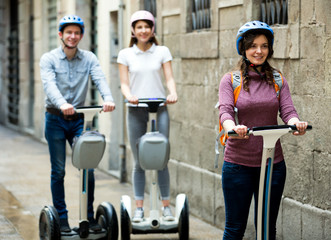 Girls and guy traveling through city by segways