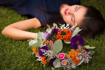 Obraz na płótnie Canvas Beautiful woman with a flower crown laying on a grass