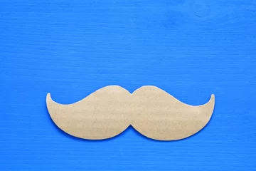 Keuken spatwand met foto Blue wooden background and paper mustache © tomertu