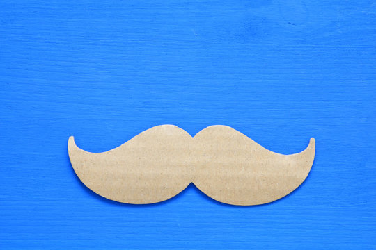 Blue wooden background and paper mustache