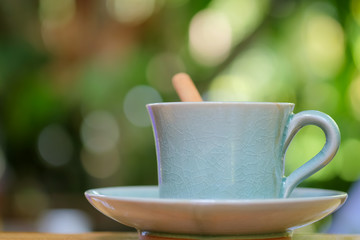 Coffee cup on wooden floor with green blurred background.
