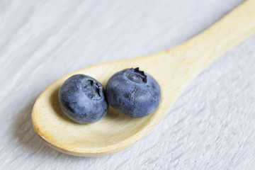  Fresh blueberries in wooden spoon on white background. Rustic style