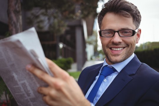 Portrait of handsome businessman reading newspaper