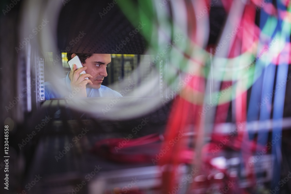 Poster technician talking on mobile phone while checking cables