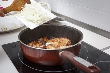 Mamá preparando en casa unas chuletas con salsa de cebolla caramelizada.