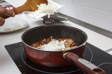 Mamá preparando en casa unas chuletas con salsa de cebolla caramelizada.